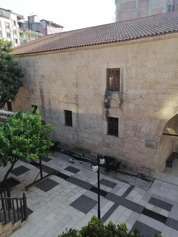 Adana Müzesi avlusunda taş yapı ve ağaç görüntüsü.