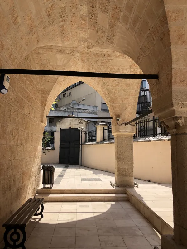 Adana müzesindeki tarihi geçit ve modern yapıların silueti.