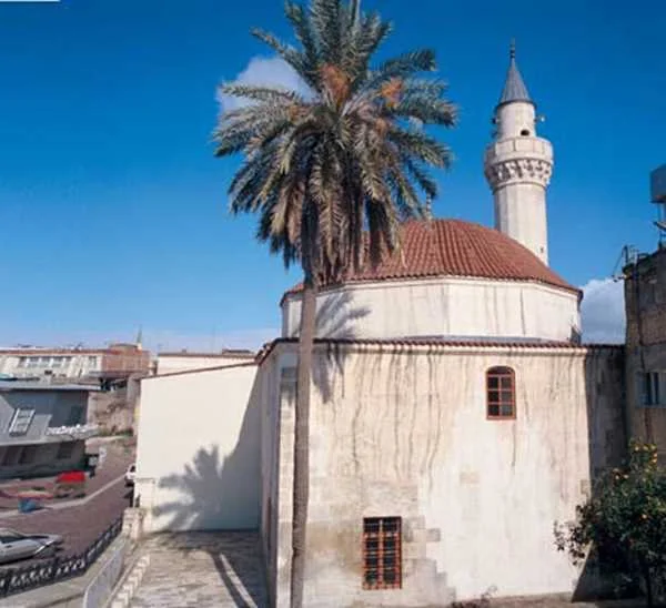 Hasan Ağa Camii'nin tarihi dokusu, palmiye gölgeleriyle buluşuyor! Hasan Ağa Camii, sıcak bir yaz günü, palmiyelerle çevrili tarihi yapı.