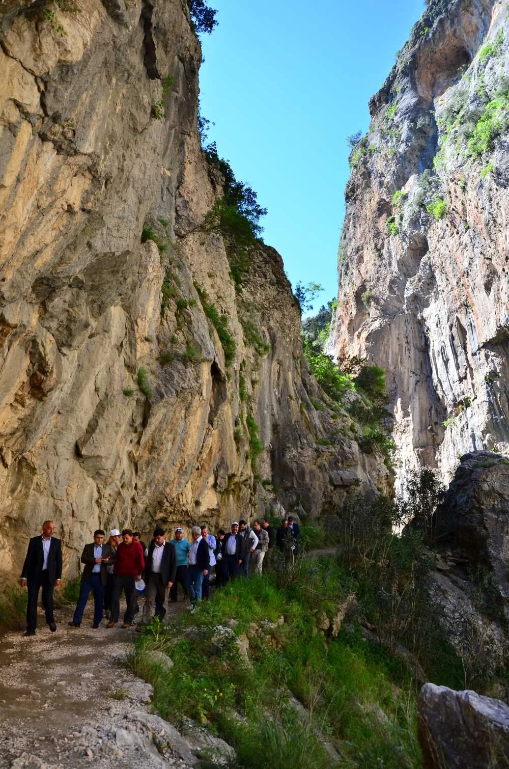 Kapıkaya Kanyonu'nda yürüyüş yapan grup, yüksek kayalar ve yeşil bitki örtüsü ile etkileyici bir atmosfer.