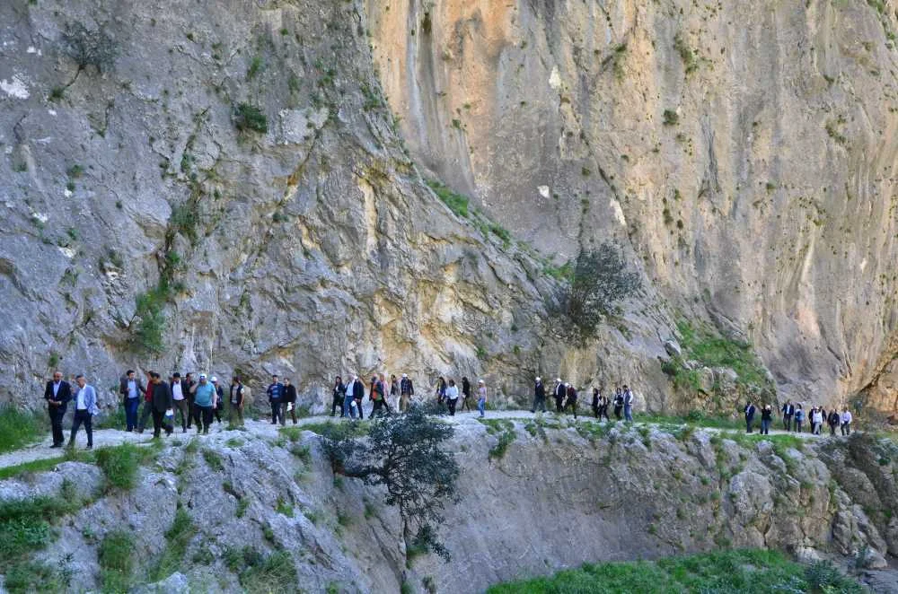 Kapıkaya Kanyonu'nda yürüyen insanlar, doğal güzellikler arasında, yaz mevsiminde keyifli bir atmosfer.