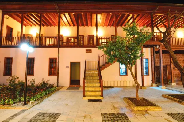 Gece çekimi, sıcak ışıklar ve ahşap detaylarla geleneksel Adana evi, doğal güzellikler içinde huzurlu bir atmosfer s