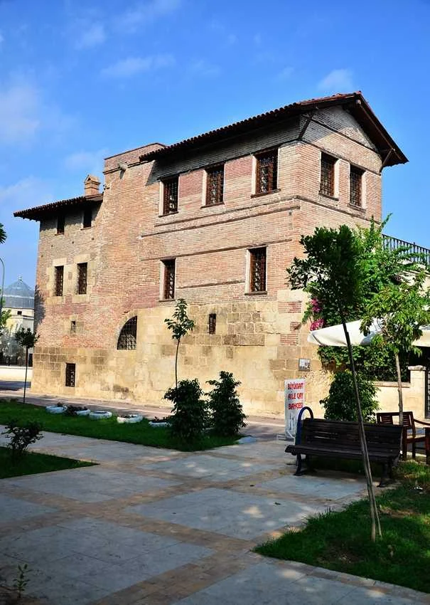 Ramazanoğlu Konağı, güneşli bir günde, doğal yeşilliklerle çevrili tarihi bir yapı.