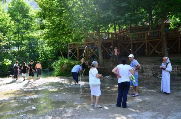 Yerköprü Mesire Alanı'nda yaz mevsiminde insanlar su kenarında eğleniyor.