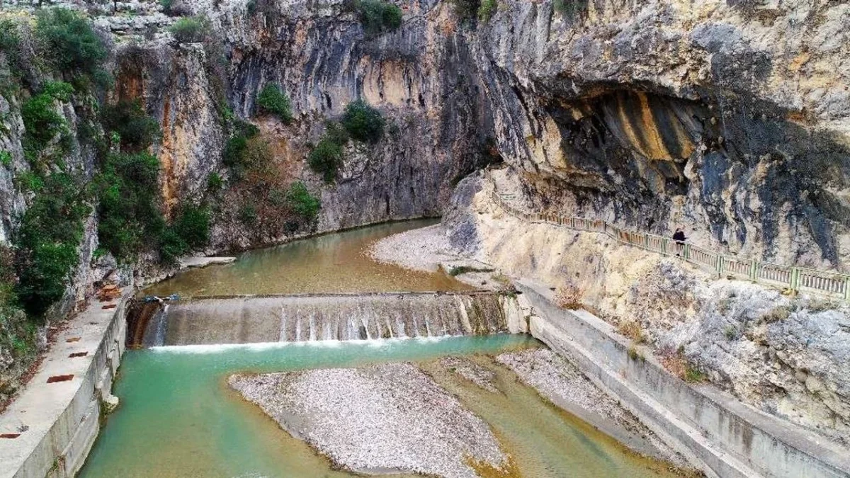 Kapıkaya Kanyonu'nda Doğanın Huzuru Yüksek kayalarla çevrili Kapıkaya Kanyonu'nda yeşil su ve küçük bir şelale.