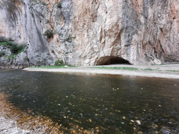 Yüksek kayalıklar arasında berrak su akıntısı ve yeşil bitki örtüsü.