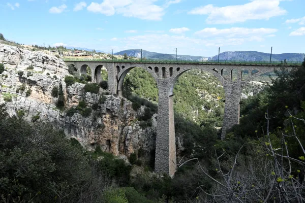 Geniş bir vadide yükselen kemerli taş köprü ve çevresindeki yeşil doğa manzarası