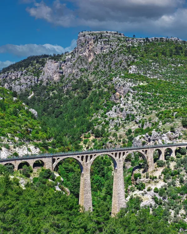 Yemyeşil dağlar arasında yer alan Varda Köprüsü, etkileyici taş yapısıyla yükseliyor.