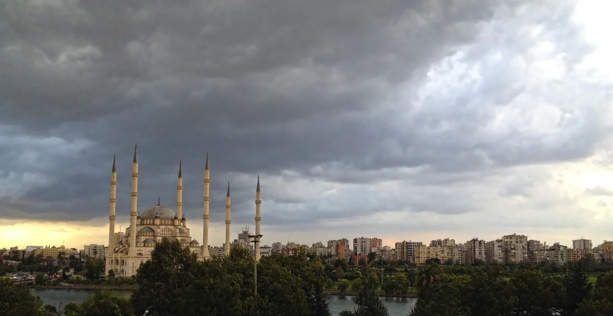 Sabancı Merkez Camii, yeşil ağaçlarla çevrili, modern apartmanlar arka planda.