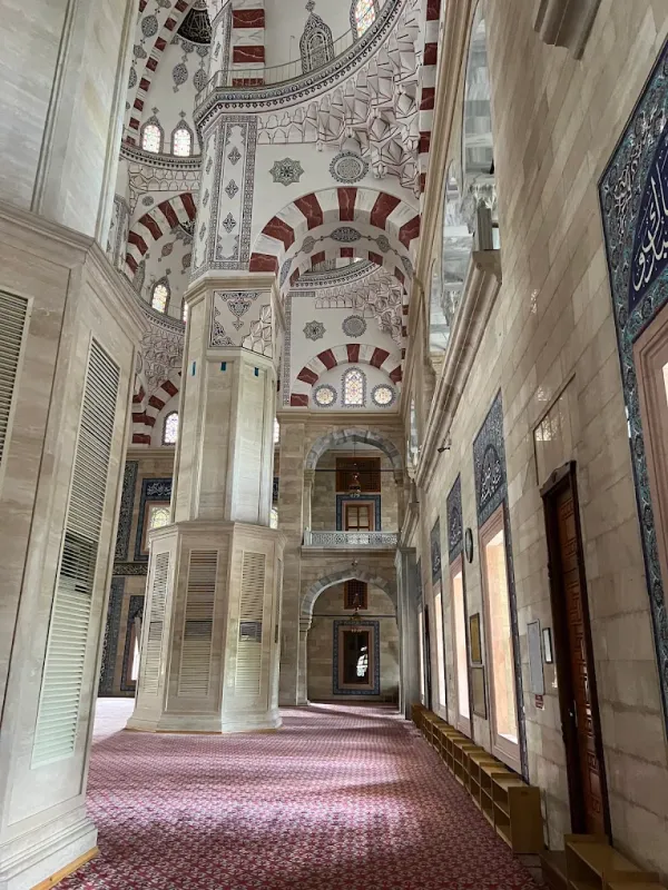 Geniş iç mekan, detaylı tavan ve renkli vitray pencerelerle dolu.