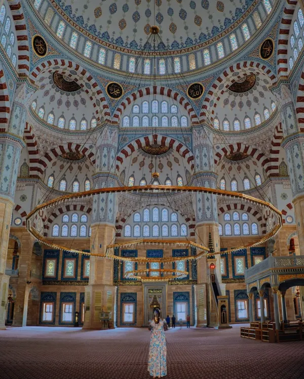 Büyük caminin yüksek tavanı, işlemeli kemerleri ve renkli pencereleriyle aydınlanan iç mekan.