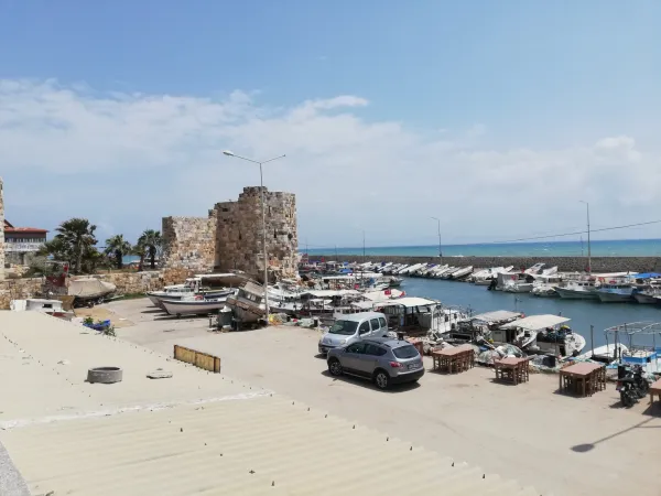 Ayas Antik Kenti limanında tekneler ve tarihi taş yapılar, huzurlu bir deniz manzarası.