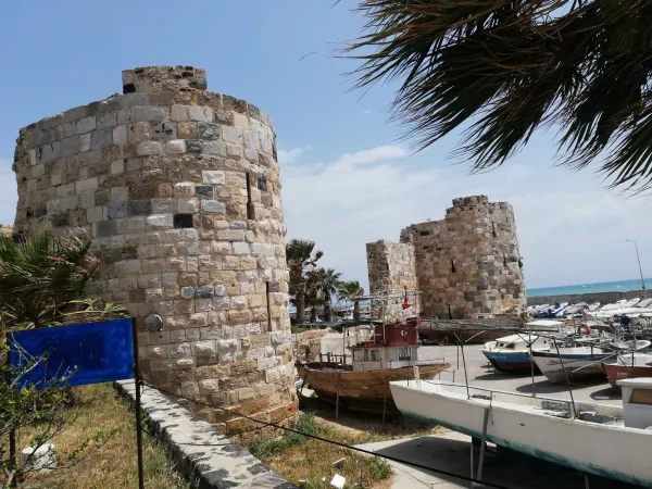 Tarihi taş kuleler ve mavi deniz, balıkçı tekneleriyle birleşiyor.