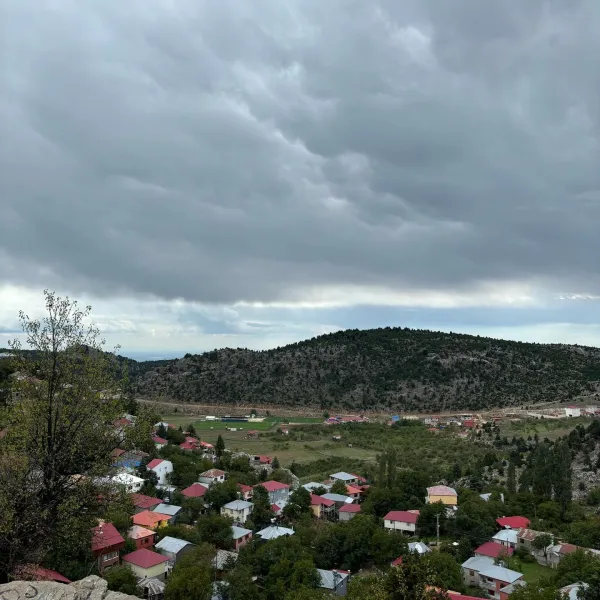 Dağlarla çevrili ağaçlarla kaplı evlerin bulunduğu Kızıldağ Yaylası görüntüsü