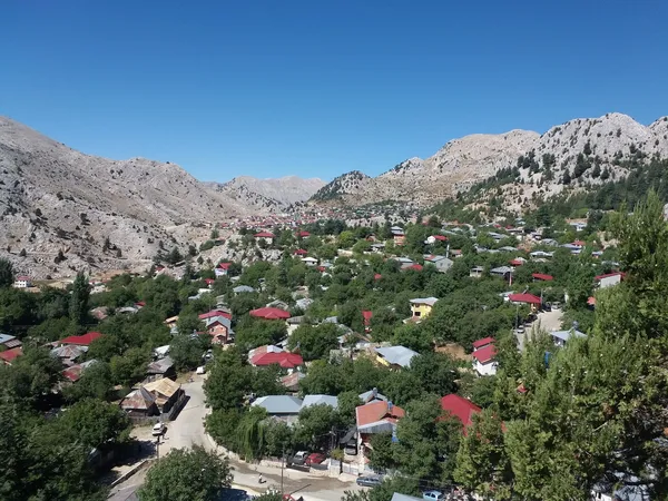 Kızıldağ Yaylası'nda yeşil ağaçlar arasında bir köy manzarası.