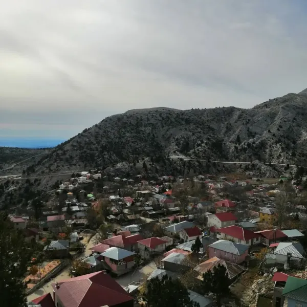 Dağlık alanda yer alan renkli evler ve ağaçlarla çevrili huzurlu bir manzara.