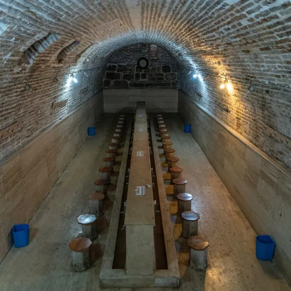 Geniş bir alanda kemerli tavan, ahşap oturma yerleri ve taş duvarlar dikkat çekiyor.