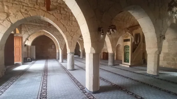 Geniş iç mekanda taş duvarlar, büyük kemerler ve tarihi avizeler dikkat çekiyor.