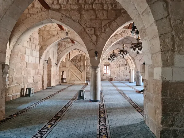 Yağ Camii'nin tarihi iç mekanında taş duvarlar ve lambalar.