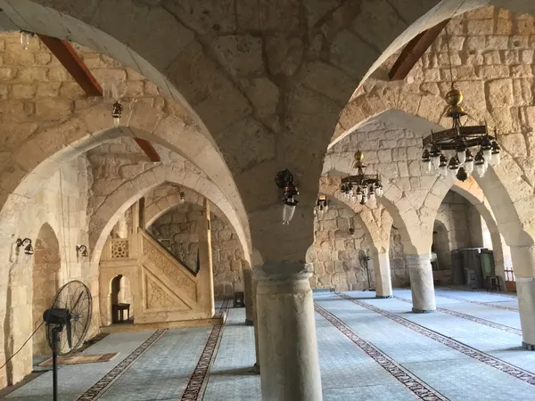 Yağ Camii'nin geniş iç mekanı, taş duvarlar ve zarif avizelerle süslenmiş.