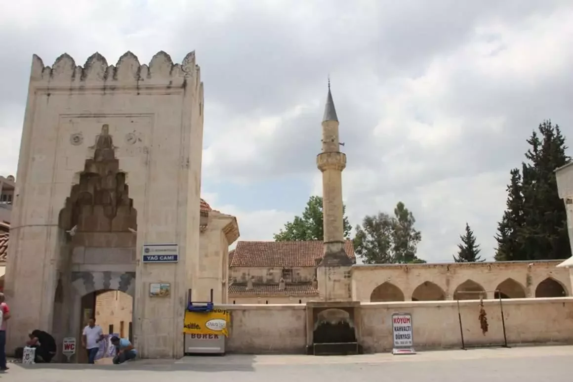 Yağ Camii: Tarihi ve Kültürel Bir Ziyaret Noktası Yerel caminin kapısı, geleneksel süslemeler ve çevresindeki yeşil ağaçlar ile birlikte görünmekte.