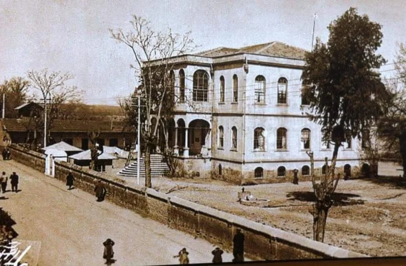Adana Tarihi Kız Lisesi: Geçmişin İzleri İki katlı tarihi bina, kayrak taşlı merdivenler ve çevresindeki ağaçlarla kış manzarası.