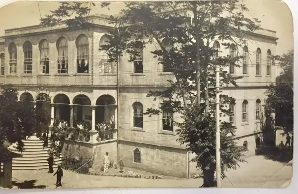 Tarihi Adana Kız Lisesi önünde kalabalık bir grup insan ve ağaçlar.