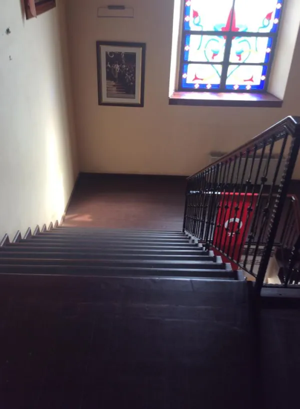 Eski fotoğraf asılı duvar ve renkli vitray pencereli merdiven görüntüsü
