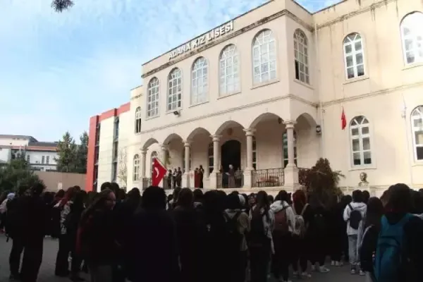 Adana Kız Lisesi önünde kalabalık öğrenci grubu, büyük tarihi bina ve Türk bayrağıyla.