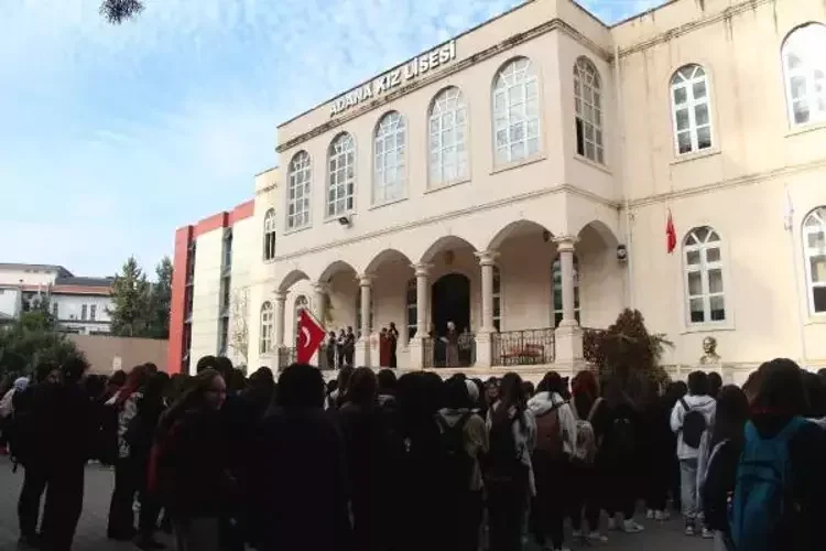Adana Tarihi Kız Lisesi'nde Öğrenci Etkinliği Adana Kız Lisesi önünde kalabalık öğrenci grubu, büyük tarihi bina ve Türk bayrağıyla.
