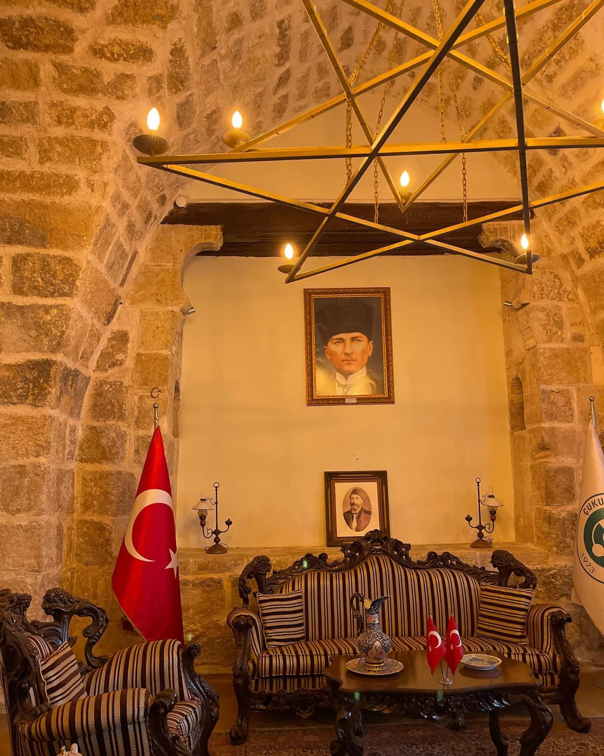 Ramazanoğlu Konağı'nın Şık İç Mekanı Taş duvarlarla çevrili, klasik döşenmiş iç mekan ve Türk bayrağı detayları.