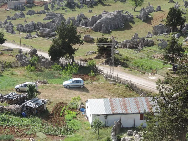 Kozan Göller Yaylası'nda taş oluşumları ve minimal ev manzarası.