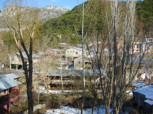 Kış mevsiminde karla kaplı dağların arkasında sıralanan renkli köy evleri