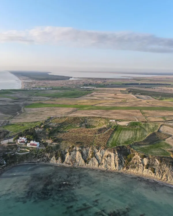 Geniş kıyı manzarasında ince kumlu plaj ve açık mavi deniz görülüyor.
