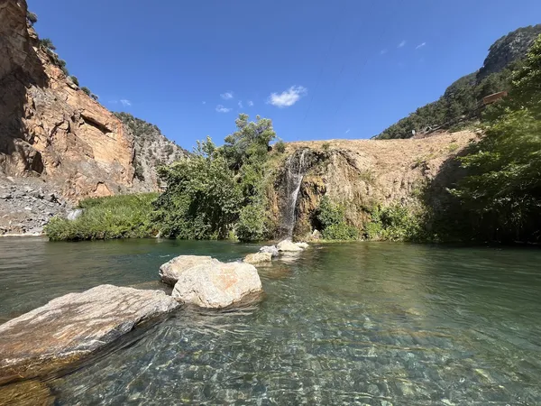 Berrak suyu olan nehir ve sağda akan küçük şelale manzarası.
