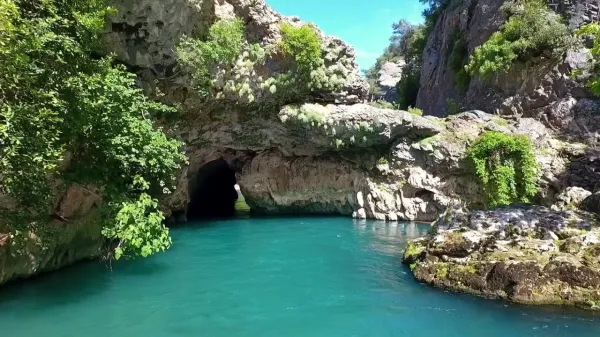 Yemyeşil bitki örtüsü ve deniz mavisi su kütlesiyle çevrili küp şelaleleri manzarası.