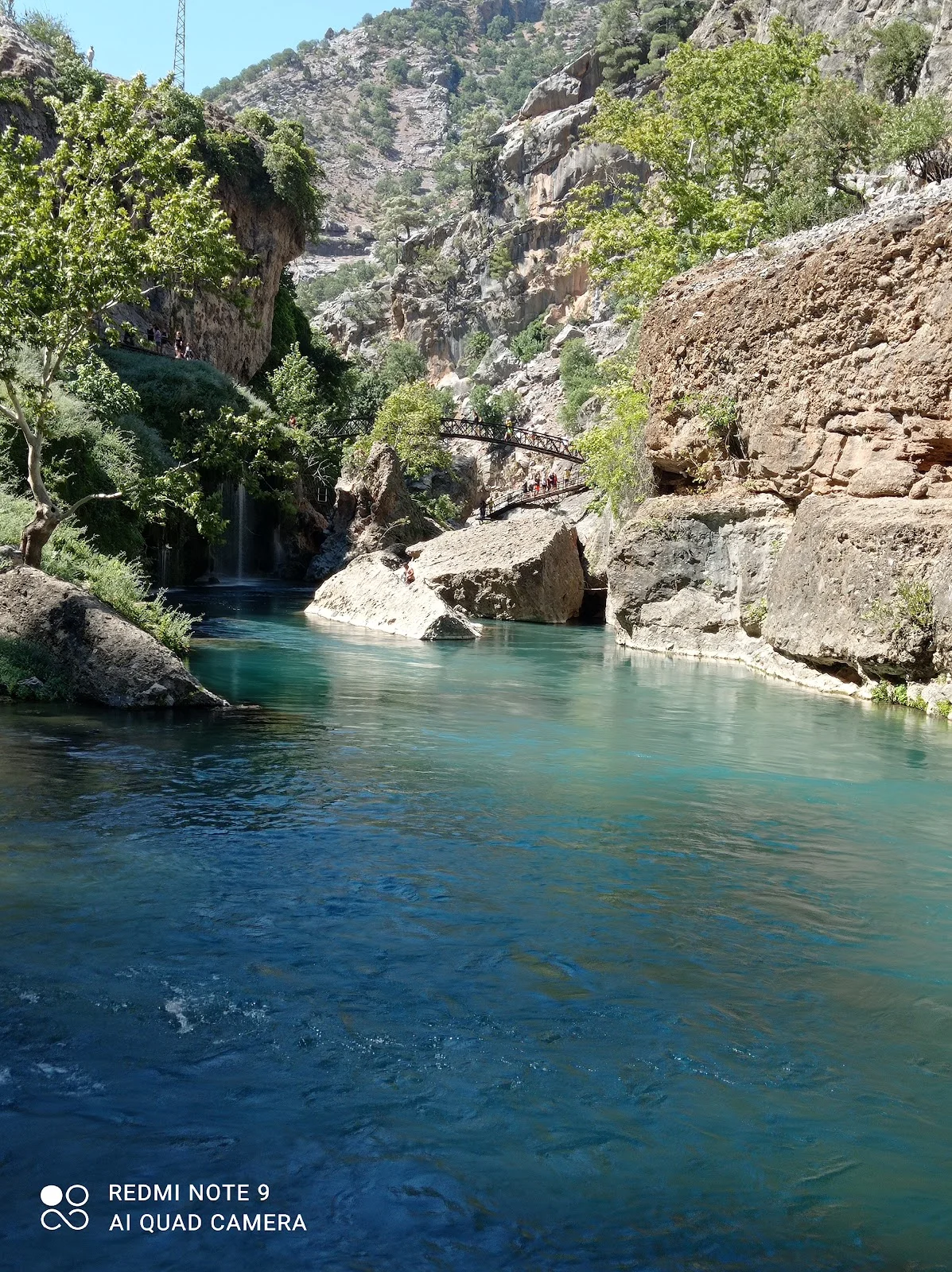 Küp Şelaleleri: Doğal Güzellik ve Huzur Küp şelaleleri ve doğal kanyon manzarası, yürüyen insanlar.