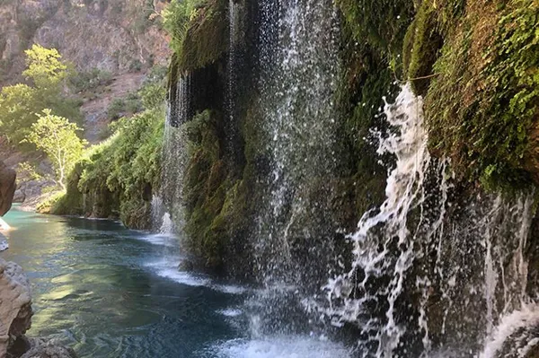 Küp şelaleleri, yeşil bitkilerle çevrili huzur veren manzara.