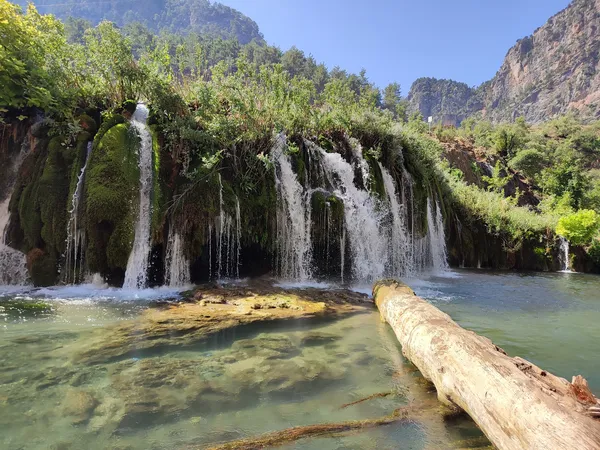 Küp şelaleleri, yeşil bitkiler ve masmavi gölet manzarası.