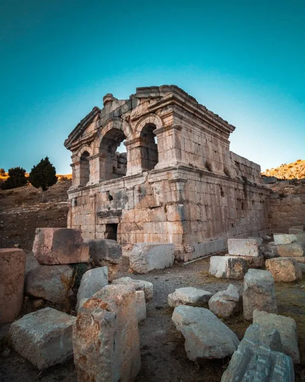 Tarihi yapının kalıntıları, yuvarlak kemerler ve dağınık taş bloklar.