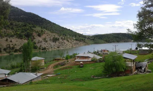 Dağlarla çevrili göl kenarındaki huzurlu bir köy manzarası