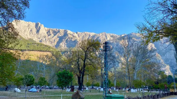 Yüksek dağlar ve yeşil ağaçlarla çevrili piknik alanı.