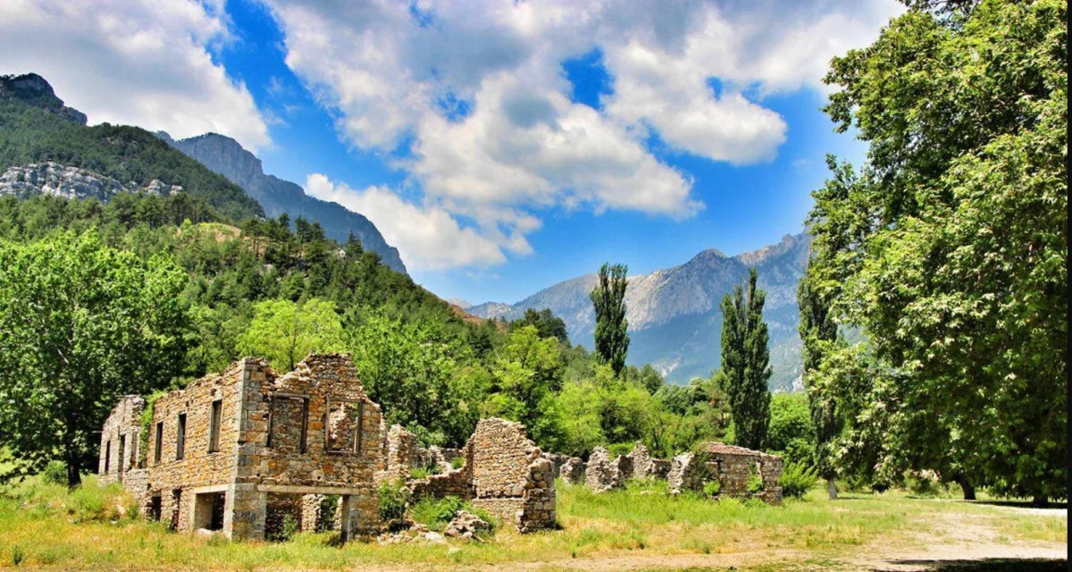 Pozantı Belemedik Yaylası'nın Doğal Güzellikleri Yeşil alanda eski taş yapının kalıntıları ve arka planda yüksek dağlar.