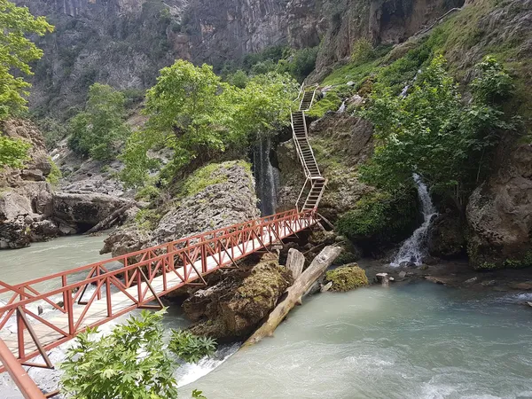 Doğal kanyon manzarası, ahşap köprü ve şelaleler.