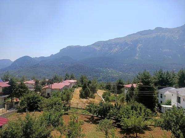 Dağlık alanda yer alan huzurlu bir yerleşim, yemyeşil dağlar ve açık gökyüzü ile çevrili.