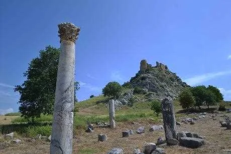 Kastabala Manzarası - Tarih ve Doğa Buluşması Kastabala Antik Kenti'nde tarihi sütunlar ve yeşil tepe, açık mavi gökyüzü altında etkileyici bir atmosfer sunuyor.