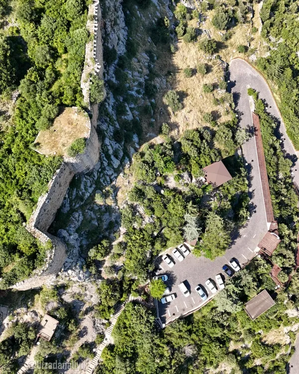 Yüksek kayalıklarda yer alan Kozan Kalesi ve çevresindeki yeşil ağaçlar.