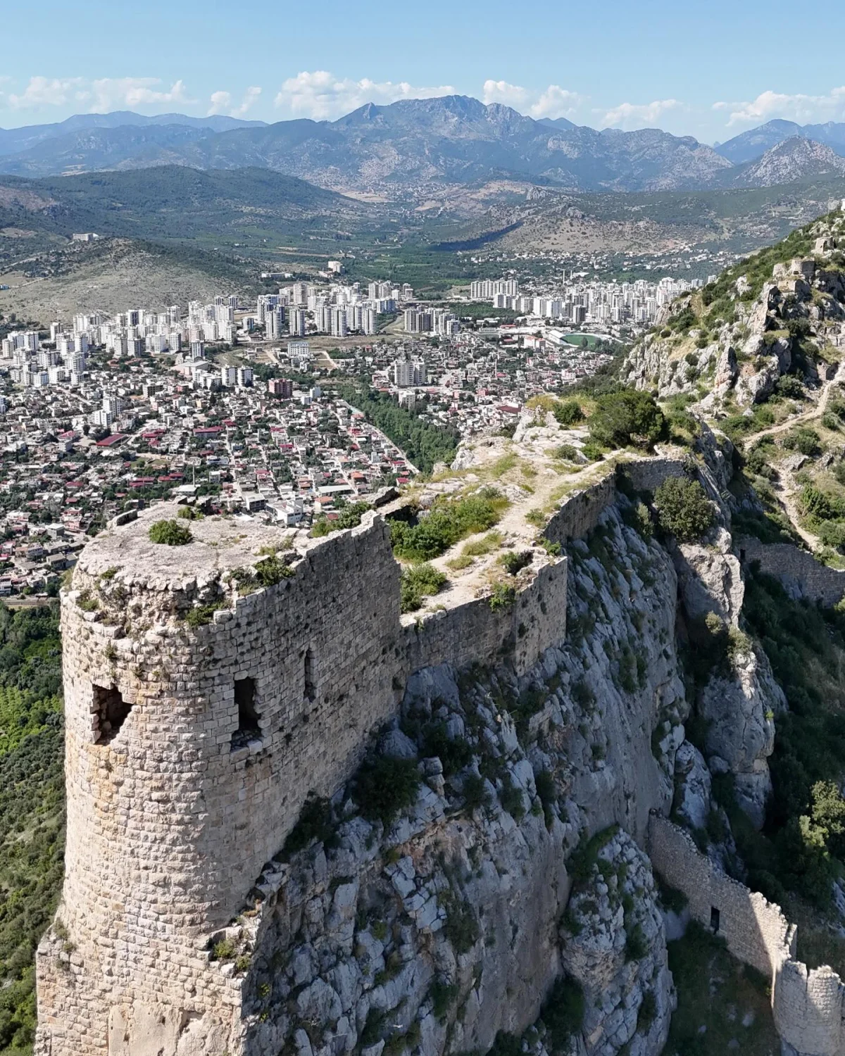 Kozan Kalesi - Tarihin İzleri, Şehir ve Dağların Arasında! Kozan Kalesi kayalık bir tepenin üzerinde, arka planda şehir manzarası ve dağlar ile çevrili.