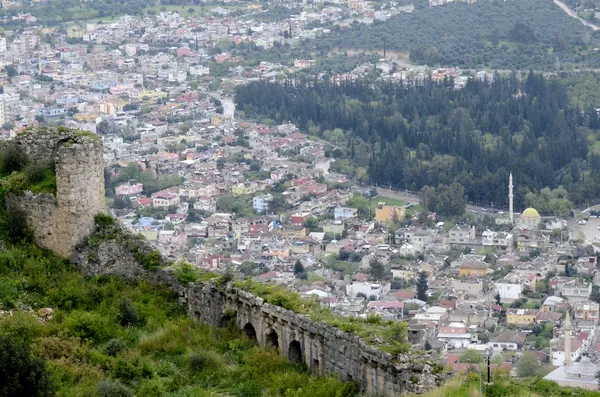 Kozan Kalesi'nin arkasında çeşitli renklerde evler ve cami minaresi görünmekte.