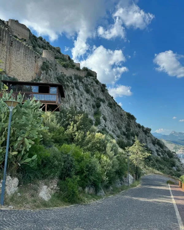 Yüksek dağ eteklerinde yer alan tarihi Kozan Kalesi'nin taş duvarları ve yeşil bitki örtüsü.